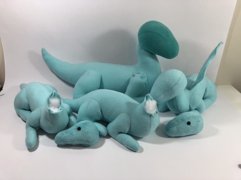 pile of partially finished dragon plushies in various sizes